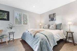a white bedroom with a bed and two tables at Wanaka Station Apartment in Wanaka