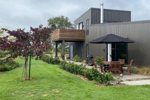 a patio with a table and an umbrella in a yard at Country Charm with Mountain views in Pukeatua