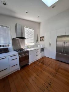 a kitchen with a stove and a wooden floor at Grafton House Villa Oasis, Central Auckland in Auckland