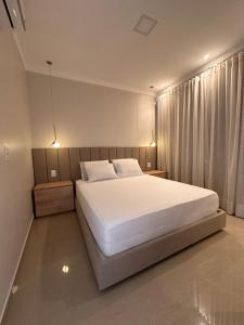 1 dormitorio con 1 cama blanca grande y cortinas en Villa Santiago II, en Manaus