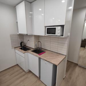 a kitchen with white cabinets and a sink and a microwave at Moriya in Batumi