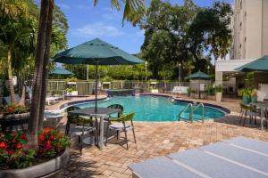 a pool with tables and chairs and an umbrella at SpringHill Suites Fort Lauderdale Airport in Dania Beach