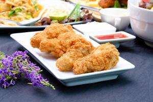 un piatto di cibo con pollo fritto su un tavolo di Slumber Surf Phuket Kata a Kata Beach