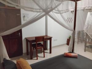 a bedroom with a desk and a table and a bed at Rusara Guest Home in Weligama
