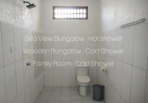 a white bathroom with a toilet and a window at Nusa Indah Bungalows in Gili Islands