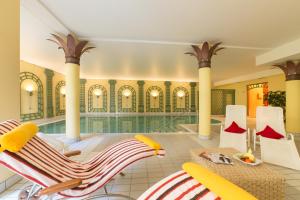 a swimming pool with two chairs and a table in a room at Hotel Bayernwinkel - Yoga & Ayurveda in Bad Wörishofen