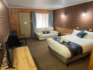 a bedroom with a bed and a brick wall at Barham Riverland Motel in Barham