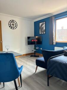 a bedroom with blue walls and a bed and a tv at Vibrant City Center Studio Apartment 6a in Norwich