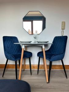 a table with two blue chairs and a mirror at Vibrant City Center Studio Apartment 6a in Norwich