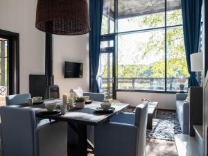 a dining room with a table and chairs and a large window at Elegant Mansion with Pools in Antoing