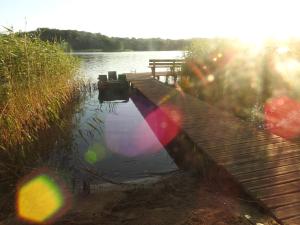 a dock on a lake with the sun reflecting in the water at Dom nad jeziorem in Sorkwity