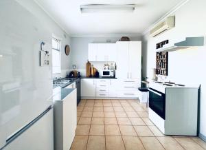 a kitchen with white cabinets and a tile floor at Treehouse Hideouts - Ground Level - Heygarth House Townhouse - Port of Echuca in Echuca