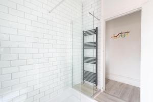 a white tiled shower with a glass door at Sophia's Retreat - 2 Floor 4 Bed Apartment - Newport - Coastal Getaway in Newport +34 photos