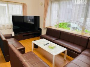 a living room with a leather couch and a tv at Y'sハウス in Chitose