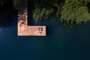 two people sitting on a wooden dock in the water at Lubie Domek in Nowa Wioska