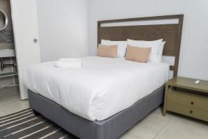 a bedroom with a large bed with white sheets and pillows at Oceanic Unit 99 - North Beach in Durban +15 photos