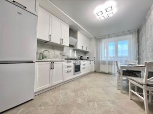 a kitchen with white cabinets and a table in it at ApartPoltava Нові апартаменти ремонт цього року ПАНОРАМА, Корпусний парк, Найкраща локація in Poltava