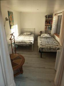 a room with two beds and a chair and a table at KITOKO L'HERAULT gite close to SALAGOU Lake in Clermont-lʼHérault