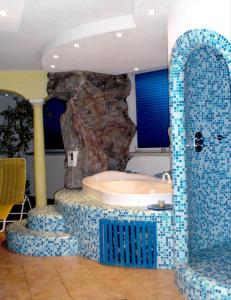 a bathroom with a tub in front of a rock at Albergo Garni Martina in Carisolo