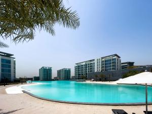 a large swimming pool with buildings in the background at Aesthetic 1Br Chrystal Lagoon in Dubai