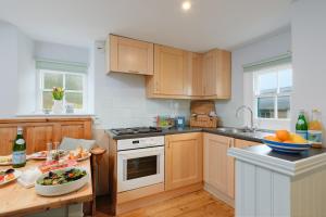een keuken met houten kasten en een tafel met een fruitschaal bij Corner Cottage in Penzance +9 foto's