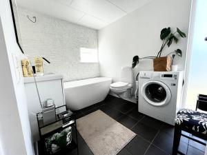 a bathroom with a washing machine and a toilet at Strandnära modernt gästhus in Stråvalla