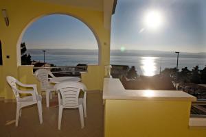 a balcony with tables and chairs and a view of the ocean at Apartments Rubic in Omiš