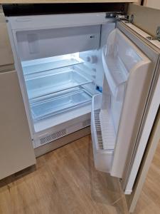 an empty refrigerator with its door open in a kitchen at M&M Apartamentai in Klaipėda