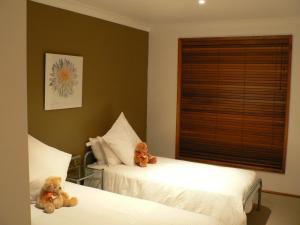 two teddy bears sitting on two beds in a bedroom at Waterfront Jervis Bay Escape Cooinda in Sanctuary Point