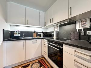 a kitchen with white cabinets and a sink and an oven at Staufner Maisonette in Oberstaufen