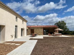 eine Terrasse eines Hauses mit einem Tisch und Stühlen in der Unterkunft Domaine du Puy Doré in Sainte-Cécile