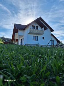 a white house in a field of green grass at Cabana iris- dotata cu ciubar si sauna in Agapia