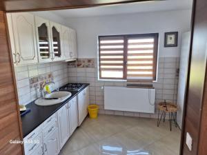 a kitchen with white cabinets and a sink and a stove at Cabana iris- dotata cu ciubar si sauna in Agapia +39 photos