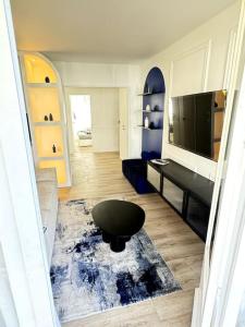 a living room with a table and a black stool at Charmant logement au bord de mer in Saint-Nazaire