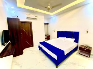 a bedroom with a blue and white bed and a television at Hotel Anupama in Bareilly