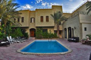a house with a swimming pool in front of it at Résidence Loued in Tozeur