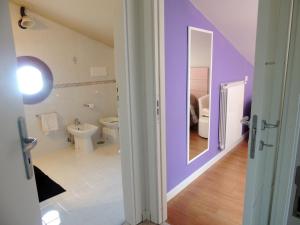 bagno con pareti viola, servizi igienici e specchio di B&B Melanella a Capaccio-Paestum