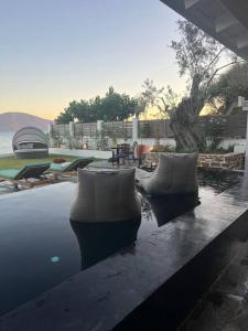 a pool of water with chairs and a table at Evia Escape - Beachfront villa in Skála