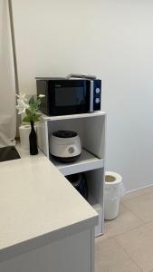 un forno a microonde su uno scaffale bianco con un vaso di fiori di Seha Stay a Suncheon