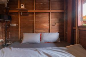 uma cama com duas almofadas num quarto com paredes de madeira em Serene Escape in Pai em Ban Wiang Nua