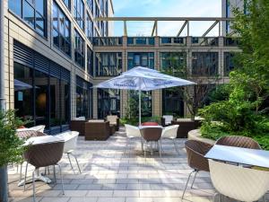 a patio with tables and chairs and an umbrella at ibis München Parkstadt Schwabing in Munich