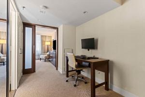 a room with a desk with a computer and a television at DoubleTree by Hilton Washington DC – Crystal City in Arlington