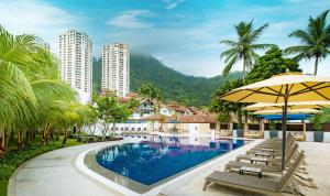 a pool at a resort with chairs and an umbrella at DoubleTree Resort by Hilton Hotel Penang in Batu Ferringhi