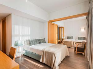 ein Hotelzimmer mit zwei Betten und einem Tisch in der Unterkunft Mercure Lisboa Almada in Almada