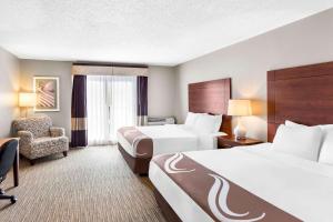 a hotel room with two beds and a chair at Quality Inn & Suites Gorham Riverside in Gorham