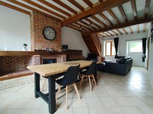 a dining room with a table and chairs and a clock at Maison de campagne individuelle in Vigneux-Hocquet