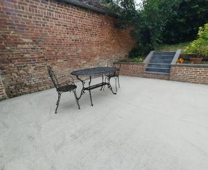 a table and two chairs sitting next to a brick wall at Maison de campagne individuelle in Vigneux-Hocquet