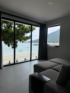 a living room with a couch and a view of the beach at Muse&Mingle Contemporary Beachfront Loft in Chaloklum