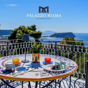 a table on a balcony with a view of the ocean at RIAMA AGRIRESORT in Naples