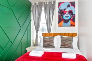 a bedroom with a red bed with a green wall at Exclusive Town Centre Home, FREE Parking, Walk to TRAIN STATION, Near AIRPORT, LUXURY Stay, GARDEN, POP ART Decor in Luton